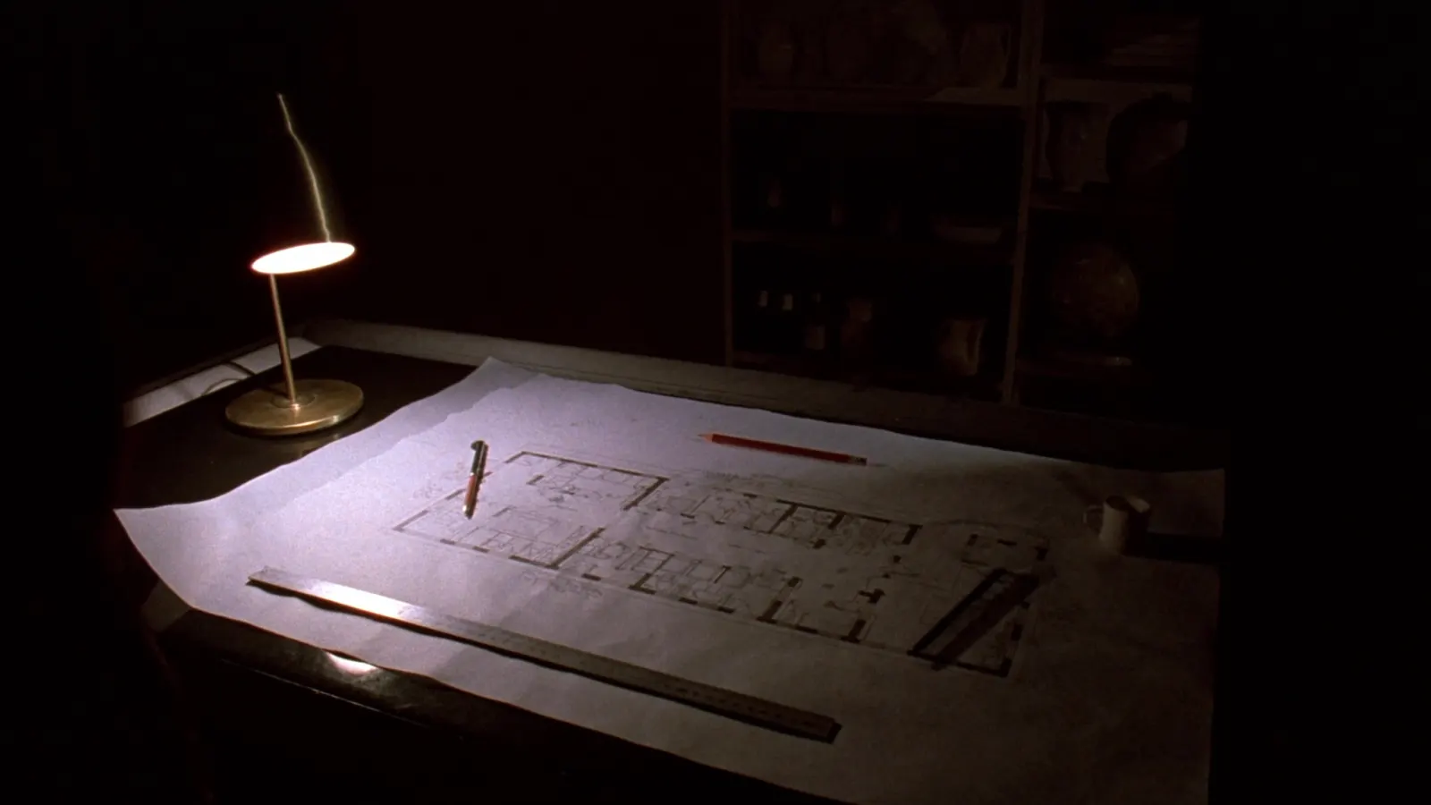 Tavolo da disegno di notte: una pianta di ristorante su carta da lucido sotto la luce di una lampada.
