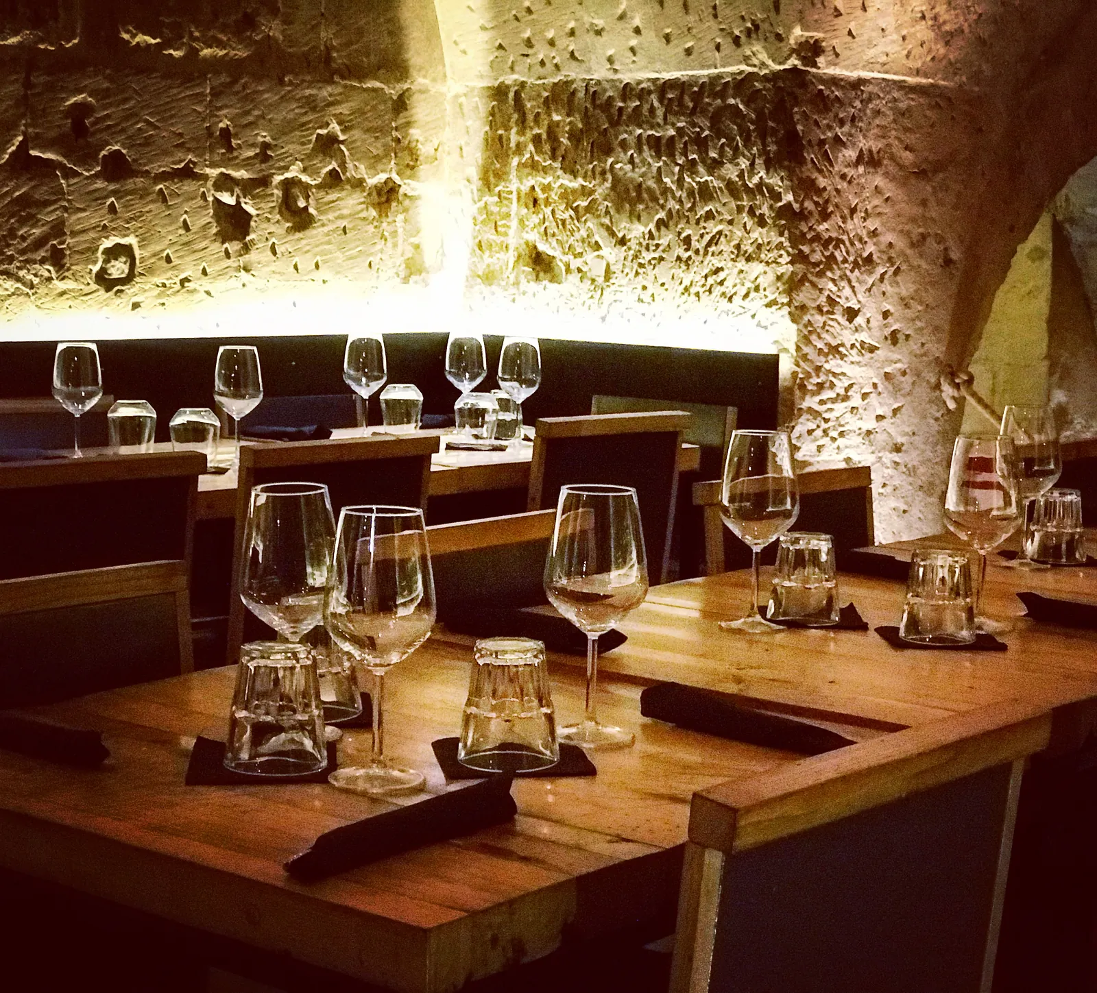 Tavoli in legno apparecchiati con calici da vino sotto una volta in pietra leccese.