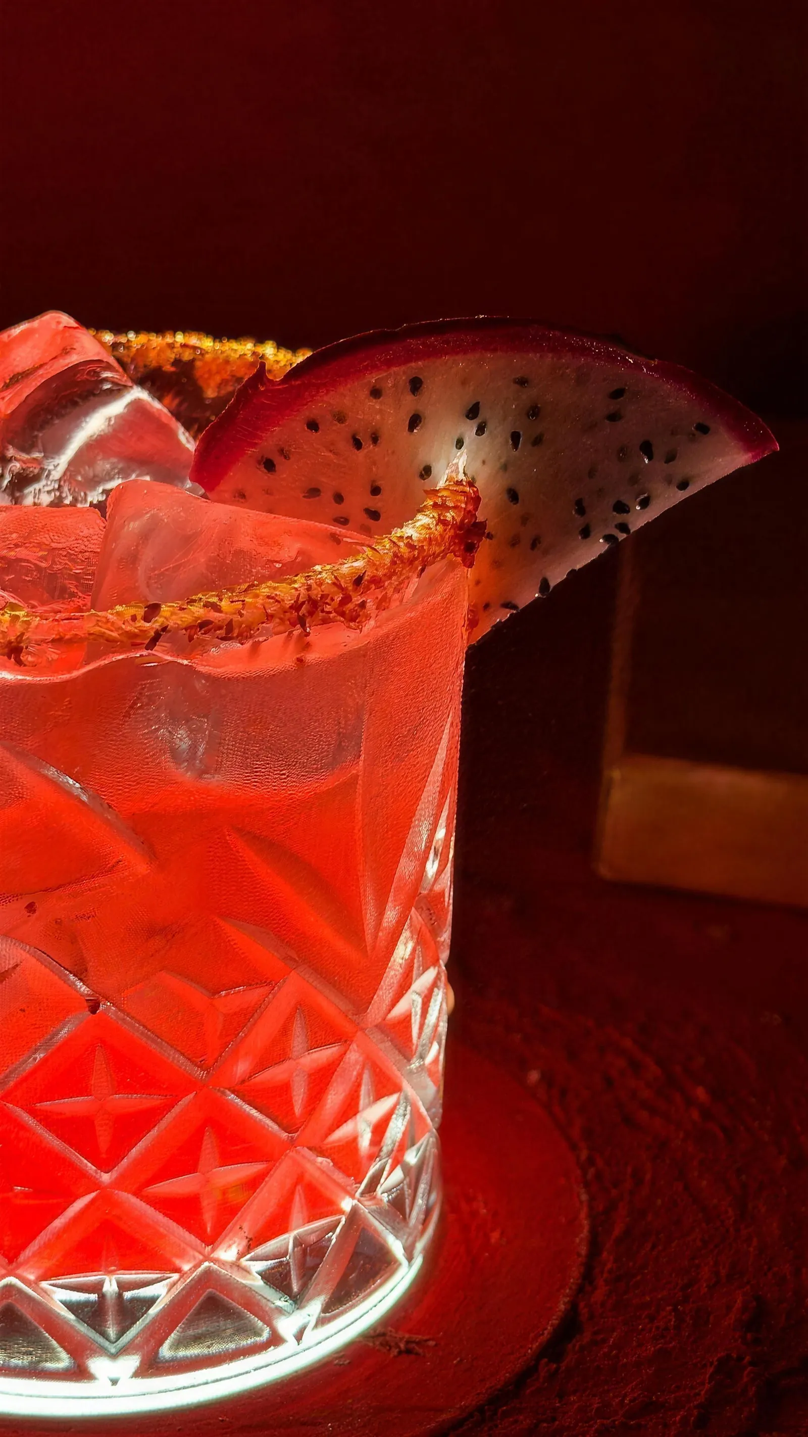 Cocktail rosso in un bicchiere di cristallo intagliato, con il bordo di sale e peperoncino.