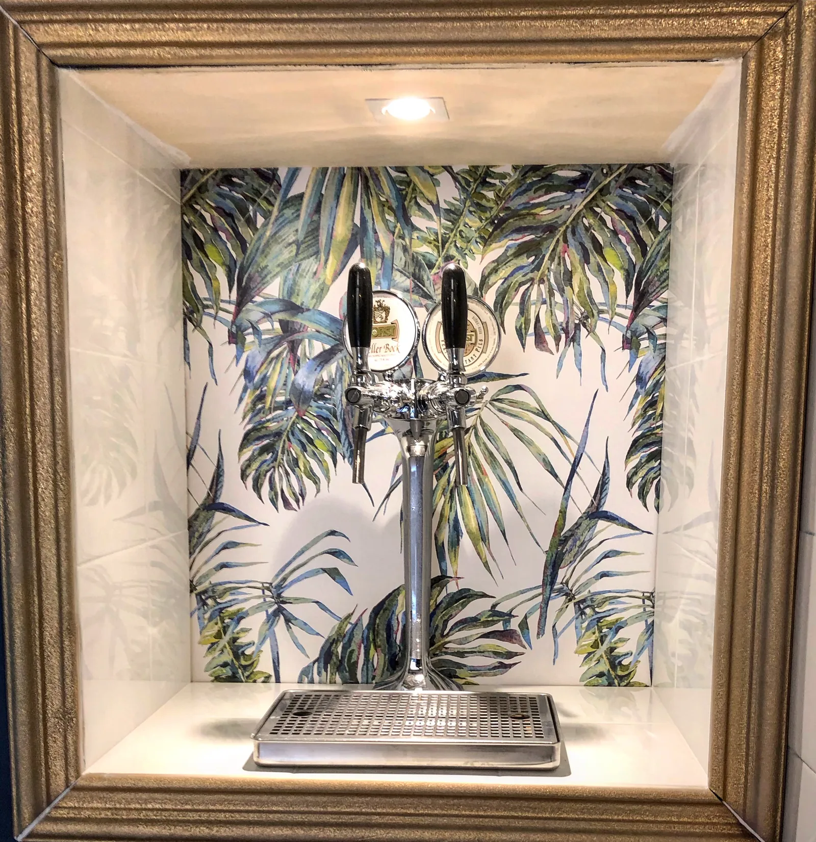 Colonna della birra alla spina incorniciata come un quadro dorato, su carta da parati tropicale.