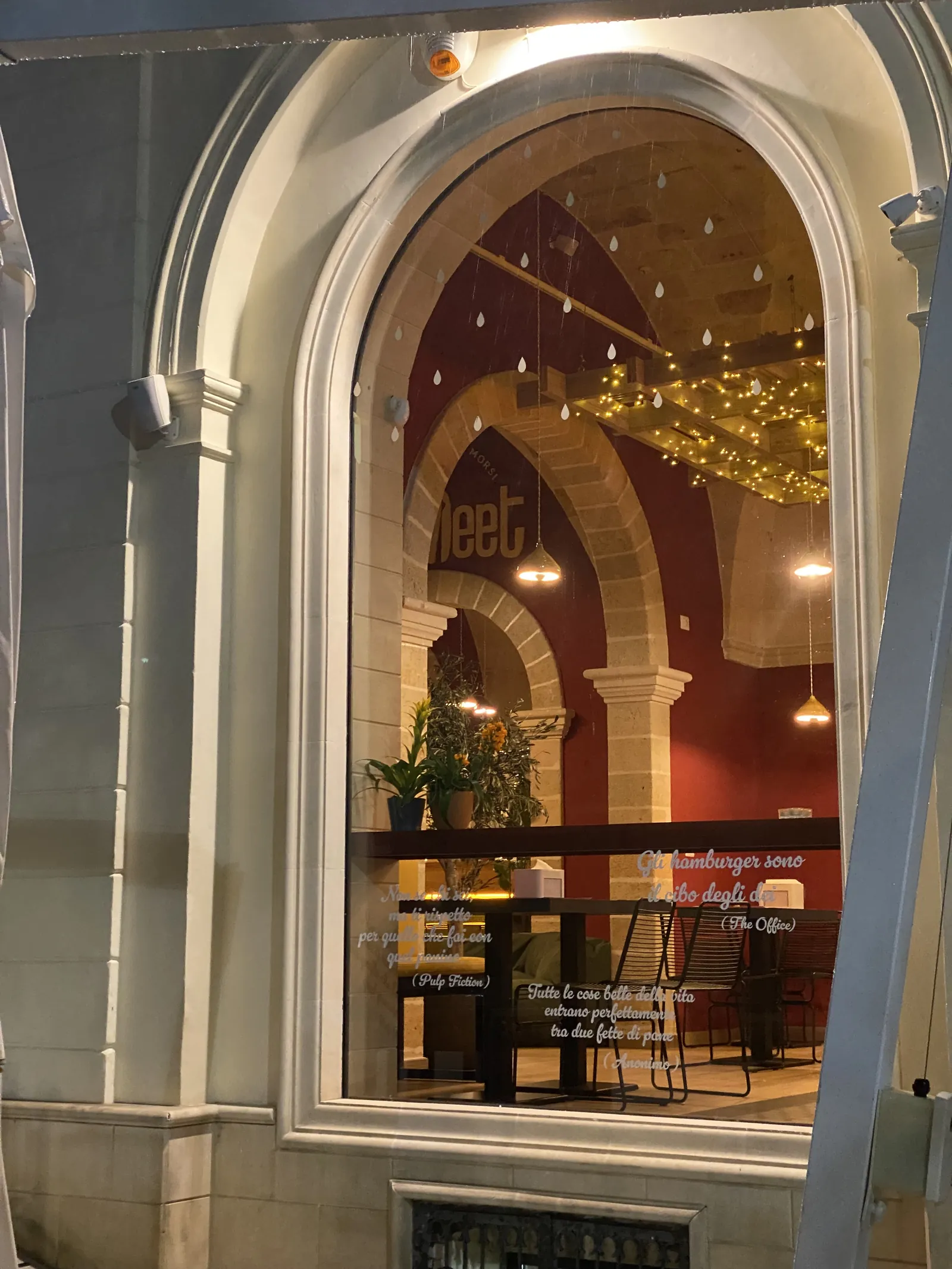Grande vetrina ad arco con cornice in pietra chiara, che lascia vedere una sala illuminata dalle pareti rosse.